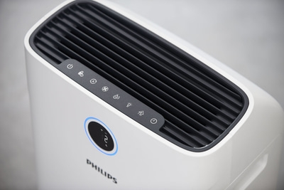 Luftreiniger von Philips mit Bedienfeld und Anzeige. Weißes Gehäuse mit schwarzem Gitter.