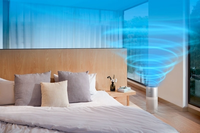 Schlafzimmer mit Bett, Kissen, Nachttisch, Luftreiniger und blauem Wirbel