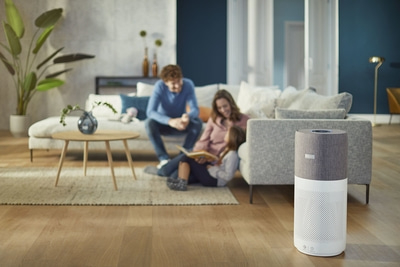 Familie liest im Wohnzimmer, Luftreiniger im Vordergrund, gemütliche Atmosphäre